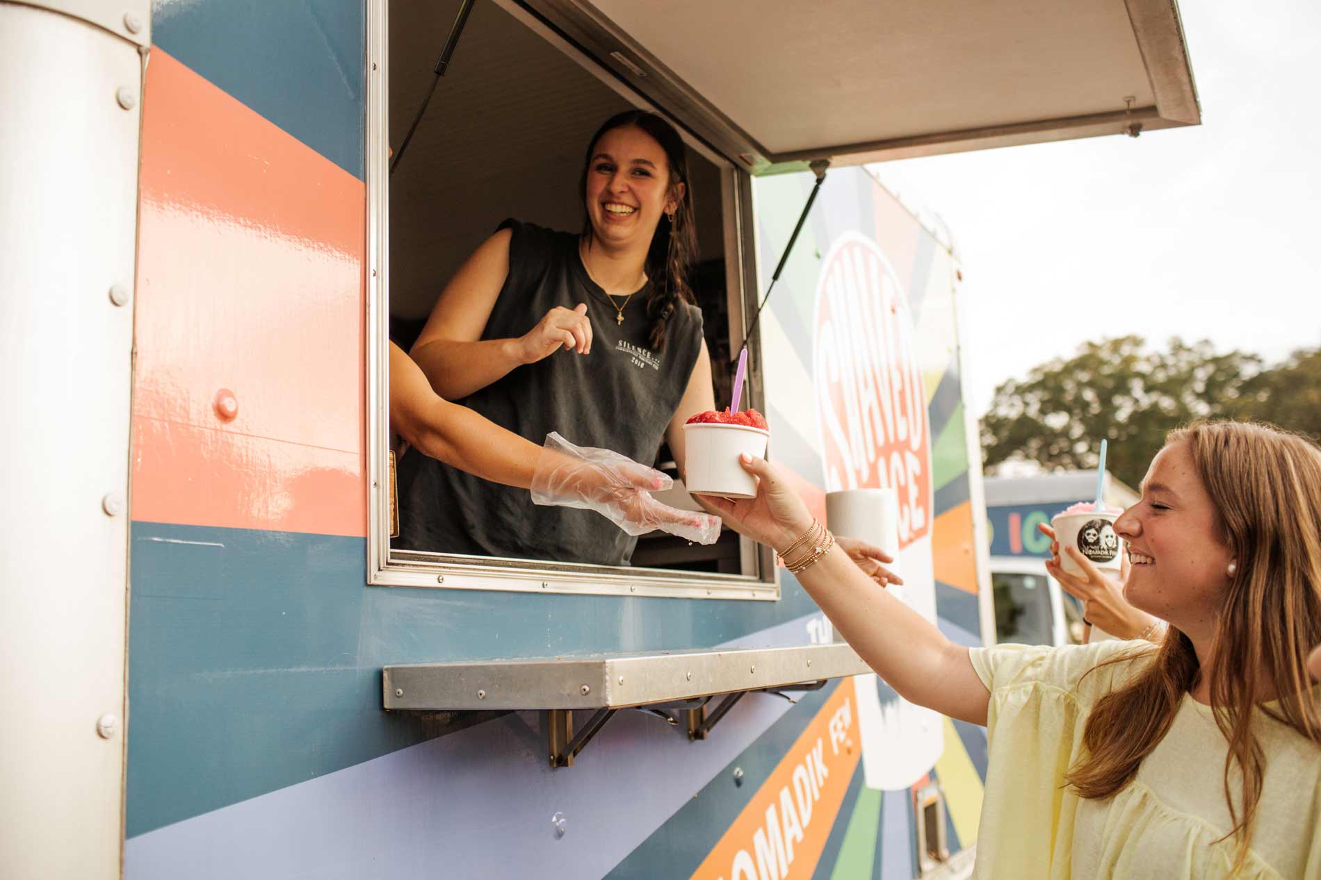 Employee serving gourmet shaved ice from The Nomadik Few shaved ice truck in Piedmont, SC experience